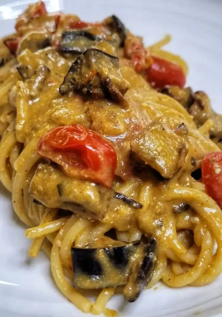 Spaghetti con crema di melanzane e pomodorini in un piatto gourmet